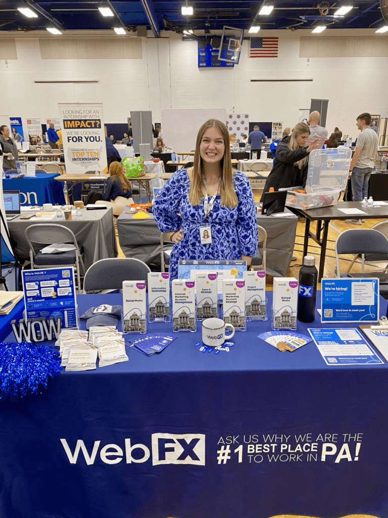 Julie em pé atrás de uma mesa Webfx em uma feira de carreira