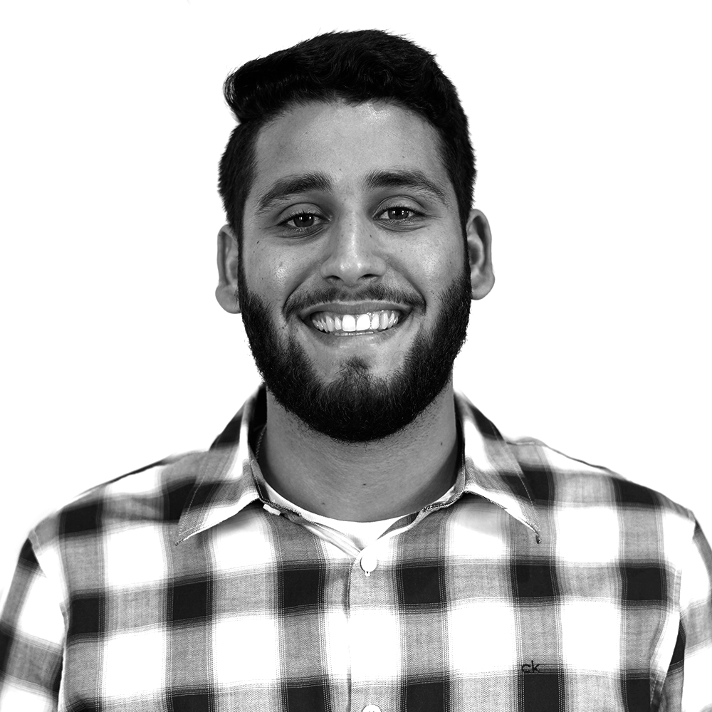 Um homem sorridente com uma barba usando uma camisa quadriculada.