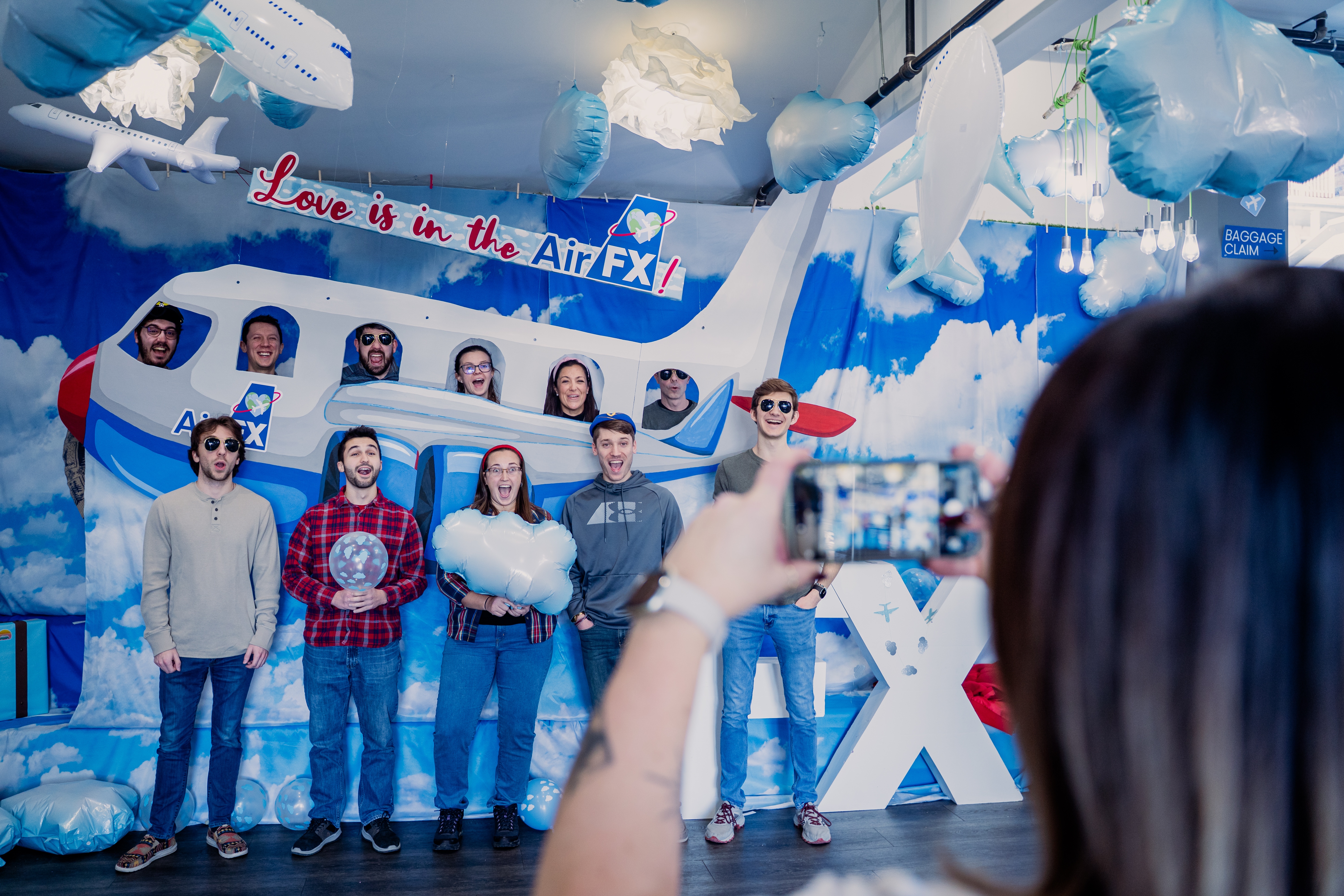 Grupo de pessoas em pé em frente a um avião de papelão, posando para uma foto