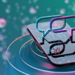 Uma ilustração renderizada em 3D exibe um smartphone em um fundo desfocado de bolhas. Bolhas rosa e azuis cercam o smartphone, que tem uma tela refletora na qual estão empilhadas duas caixas de diálogo. A caixa de diálogo superior é rosa e azul e mostra a palavra "Ai". A caixa de diálogo inferior é um reflexo da caixa de diálogo superior.